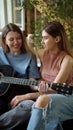 Two lgbt girls are sitting in the lining room on the sofa, playing guitar and singing songs, slow motion