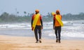 Two Lifeguards on duty at the tropical beach, Both carrying rescue tubes on their shoulders and walking on the tropical sandy Royalty Free Stock Photo