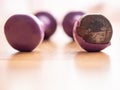 Two light small purple color dumbbell on a wooden floor. One has serious damage to plastic surface. Hard fitness workout concept.