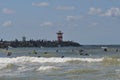 Two lighthouses and many surfers in the water of the sea. Royalty Free Stock Photo