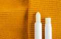 Two lip balms on the orange knitted background. Winter lip care sticks with beeswax, honey, panthenol and shea butter. Copy space.