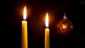 Two lit candles on a dark background near a Christmas tree Royalty Free Stock Photo