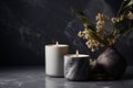 Two lit candles in grey marbled holders set a serene mood, paired with dried flowers against a dark, marbled backdrop Royalty Free Stock Photo