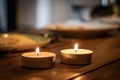 two lit candles on top of a brown wooden table, with plate in the background Royalty Free Stock Photo