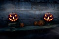 Two lit halloween Jack O Lanterns on the left and right on a dark blue night stone plinth