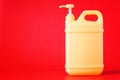 Two-liter yellow plastic canister with pump dispenser and cleaning disinfectant liquid. Red background