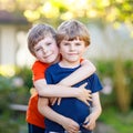 Two little active school kids boys, twins and siblings hugging on summer day. Cute brothers, preschool children and best