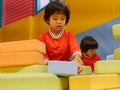 Two little Asian baby girls, sisters, stacking up foam building bricks / blocks together at an indoor playground Royalty Free Stock Photo