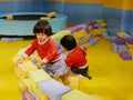 Two little Asian baby girls, sisters, stacking up foam building bricks / blocks together at an indoor playground Royalty Free Stock Photo