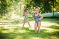 The two little baby girls playing with garden sprinkler. Royalty Free Stock Photo