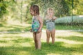 The two little baby girls playing with garden sprinkler. Royalty Free Stock Photo