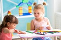 Two little beautiful girls draw with colorful pencils