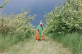 two little beautiful girls in identical dresses hugging their mother in the apple orchard before the rain. Royalty Free Stock Photo