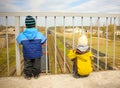 Two little boy look at the approaching train from the footbridge Royalty Free Stock Photo