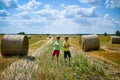 Two little boy stand among round haystack. Field with round bales after harvest under blue sky. Big round bales of straw, sheaves Royalty Free Stock Photo