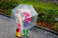 Two little boys, best friends and siblings walking with big umbrella outdoors on rainy day. Preschool children having Royalty Free Stock Photo