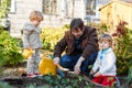 Two little boys and father planting seeds and strawberry and tomato seedlings in vegetable garden, outdoors. Happy Royalty Free Stock Photo