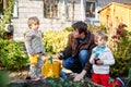 Two little boys and father planting seeds and strawberry and tomato seedlings in vegetable garden, outdoors. Happy Royalty Free Stock Photo