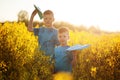 Two little boys friends with blue paper plane in summer yellow field. Brother love. Concept friendship.