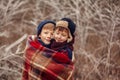 Two little boys friends hug under warm blanket in winter forest. . Brother love. Concept friendship