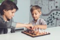 Two boys play chess sitting at a table and are bored. Royalty Free Stock Photo