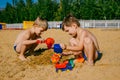 Two little boys playing with cars on a sandy beach Royalty Free Stock Photo