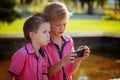 Two little boys playing games on mobile phone in sunny day. Royalty Free Stock Photo