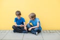 Two little boys playing with mobile phone sitting on the bench outdoors Royalty Free Stock Photo