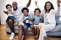 Two little boys playing video games while sitting with their family. African american family of five having fun and Royalty Free Stock Photo