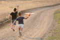 Two little boys running on a dirt road launching toy planes, summer outdoor games Royalty Free Stock Photo