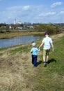 Two little boys walking on the river bank on horizon line background. Brothers holding hands. Royalty Free Stock Photo