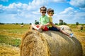 Two little boy stand among round haystack. Field with round bales after harvest under blue sky. Big round bales of straw, sheaves Royalty Free Stock Photo