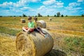 Two little boy stand among round haystack. Field with round bales after harvest under blue sky. Big round bales of straw, sheaves Royalty Free Stock Photo