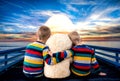 Two little brothers with the bear watching the sunset. Royalty Free Stock Photo