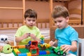 Two little caucasian friends playing with lots of colorful plastic blocks indoor. Active kid boys, siblings having fun building an Royalty Free Stock Photo