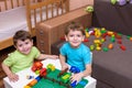 Two little caucasian friends playing with lots of colorful plastic blocks indoor. Active kid boys, siblings having fun building an Royalty Free Stock Photo