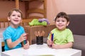 Two little caucasian friends playing with lots of colorful plastic blocks indoor. Active kid boys, siblings having fun building an Royalty Free Stock Photo