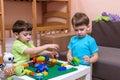 Two little caucasian friends playing with lots of colorful plastic blocks indoor. Active kid boys, siblings having fun building an Royalty Free Stock Photo