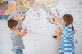 Two little caucasian kids in striped shirt measuring with tape world map during vacation travel planning