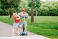 Two little Caucasian preschool children fighting in park outside. Boy and girl can not share one scooter. Royalty Free Stock Photo