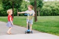 Two little Caucasian preschool children fighting in park outside. Boy and girl can not share one scooter. Royalty Free Stock Photo