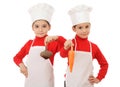 Two little chief-cookers holding a vegetables