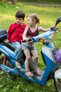 Two little children on a blue scooter on Royalty Free Stock Photo