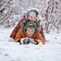Two little children, boy brothers playing and lying in snow outdoors during snowfall. Active leisure with children in winter on co Royalty Free Stock Photo