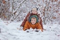 Two little children, boy brothers playing and lying in snow outdoors during snowfall. Active leisure with children in winter on co Royalty Free Stock Photo