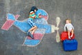 Two little children, kid boy and toddler girl having fun with with airplane picture drawing with colorful chalks on Royalty Free Stock Photo