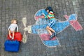 Two little children, kid boy and toddler girl having fun with with airplane picture drawing with colorful chalks on Royalty Free Stock Photo