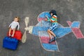 Two little children, kid boy and toddler girl having fun with with airplane picture drawing with colorful chalks on Royalty Free Stock Photo