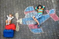 Two little children, kid boy and toddler girl having fun with with airplane picture drawing with colorful chalks on