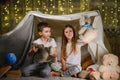 Two little children play at home in the evening to build a camping tent to read books with a flashlight and sleep inside Royalty Free Stock Photo